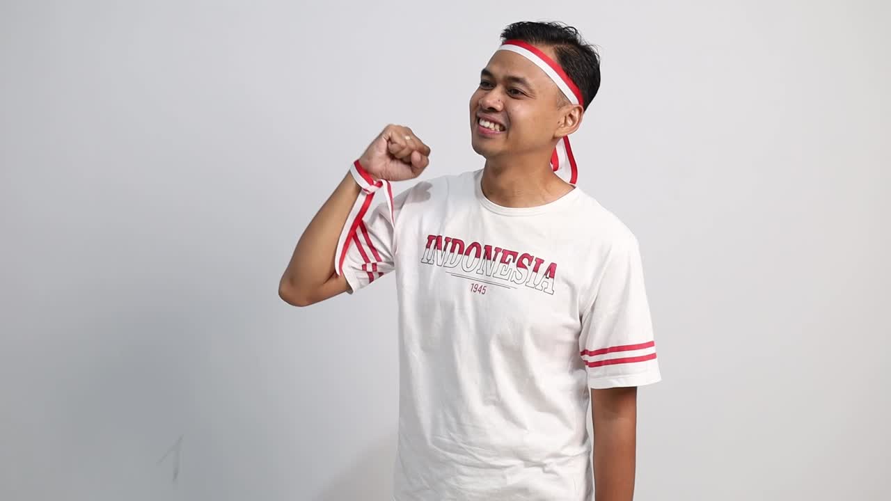 Asian man giving salute to sideways, celebrate Indonesian independence day on 17 August isolated over white background