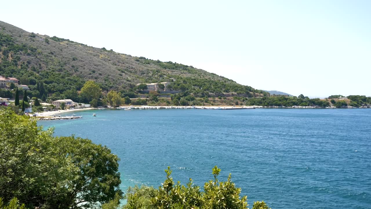 View of the beach on Corfu Island, blue sea, and mountains in the background