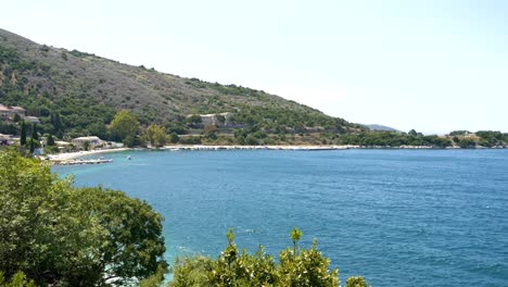 View-of-the-beach-on-Corfu-Island,-blue-sea,-and-mountains-in-the-background