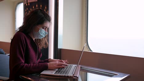 woman in mask working on laptop on cruise ship