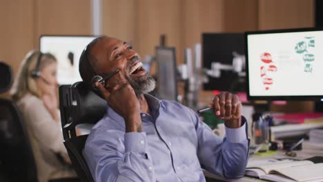 Professional-businessman-laughing-while-talking-on-phone-headset-in-modern-office-in-slow-motion