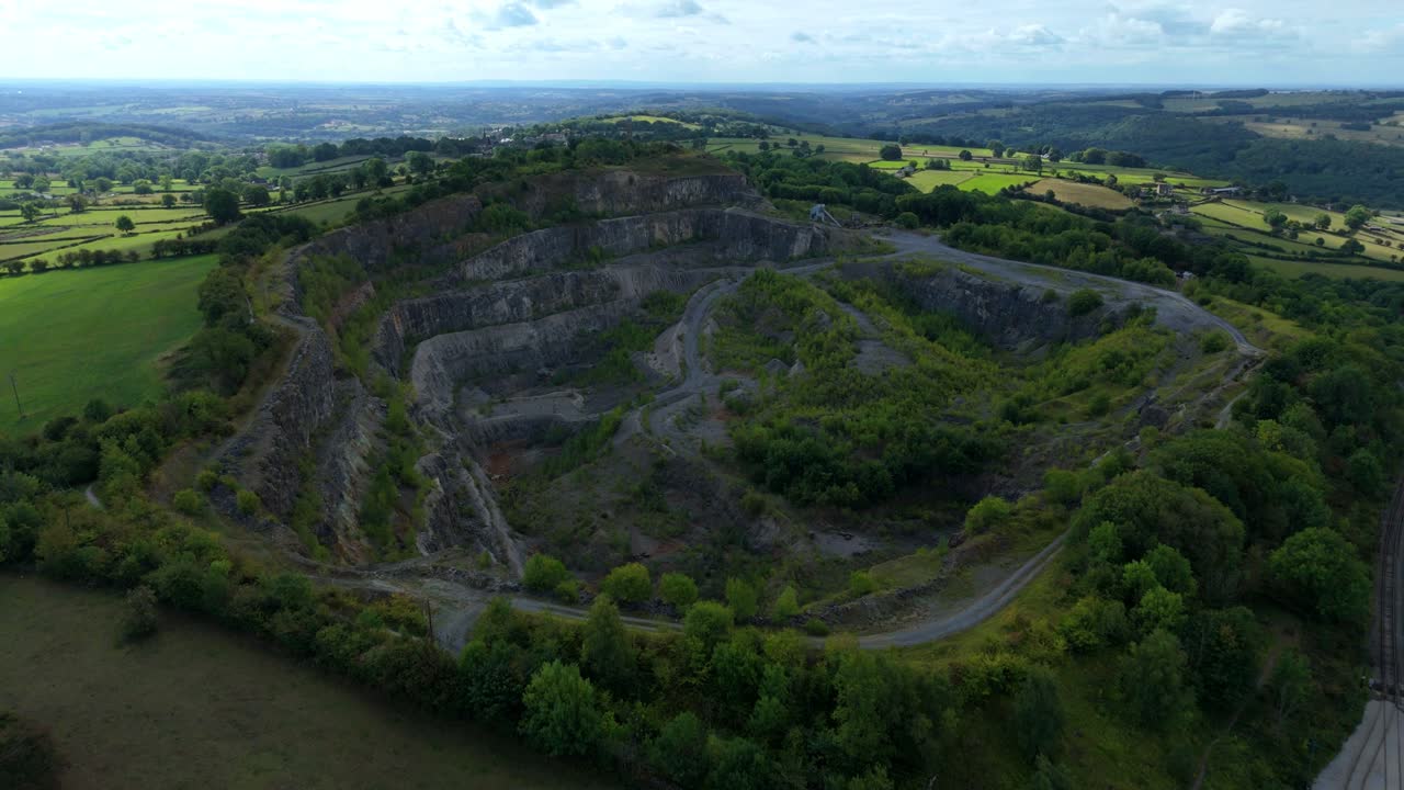 Aerial drone view of Crich Quarry in Derbyshire Dales showing stone extraction pits, rolling green hills, and rugged industrial landscape in the UK