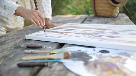 happy girl artist paints a picture on the background of summer nature hobbies creativity happy girl artist paints a picture on the background of summer nature a woman with a brush and a palette makes a sketch hobbies creativity leisure time