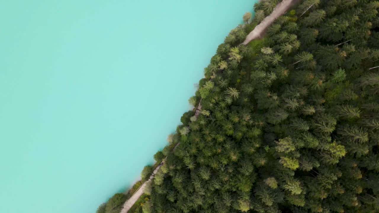 volando hacia arriba girará lentamente sobre el lago azul con bosque y camino