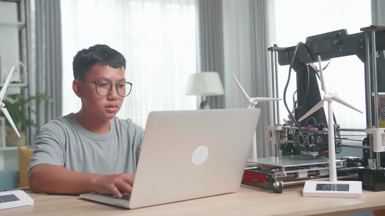 Boy learning about renewable energy with 3D printer and laptop
