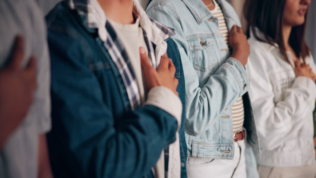 personas de pie juntas con las manos sobre sus corazones