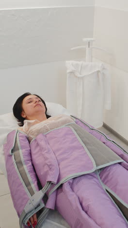 mujer haciendo tratamiento de procedimiento de presoterapia en un salón de belleza acostada en una cama médica y relajándose