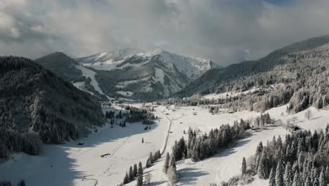 Drone-aerial-view-flying-over-picturesque-mountain-ridge-snowy-landscape-with-snow,-sunlight-and-blue-sky