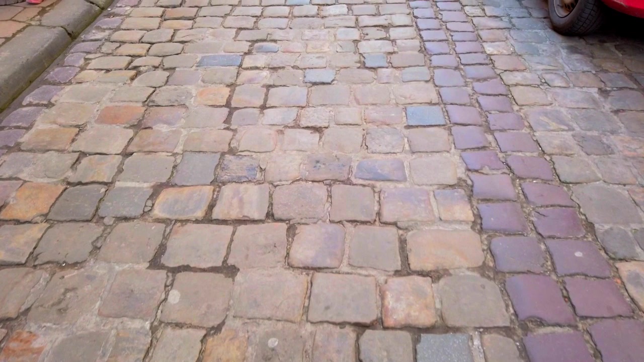 Old street of paving stone and parked cars.