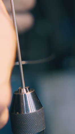 cu: professional jeweler takes off gold spiral from coiling tool on blurred background in old workshop closeup