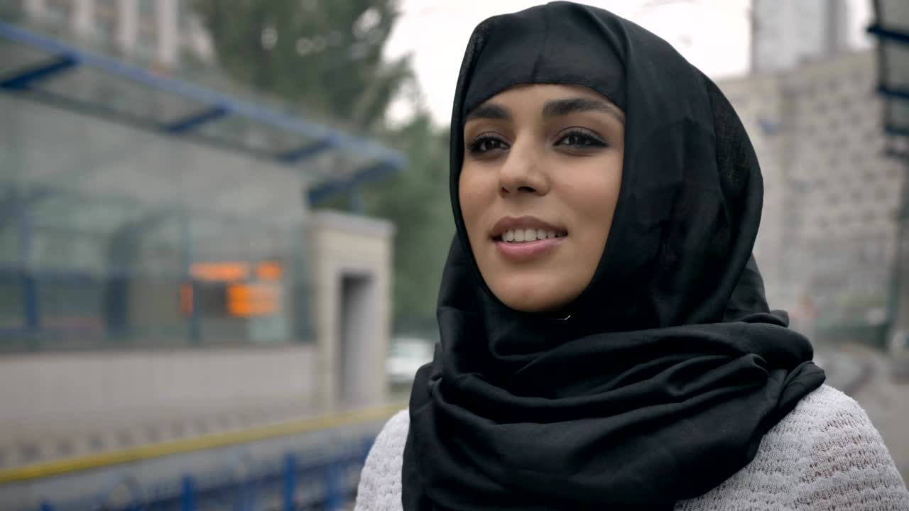 Young dreaming muslim woman in hijab is waiting for train, raining, religion concept, urban concept. weather concept
