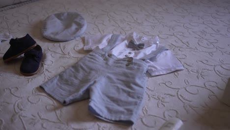 infant baptism outfit on display with suspenders, shoes, and a cap