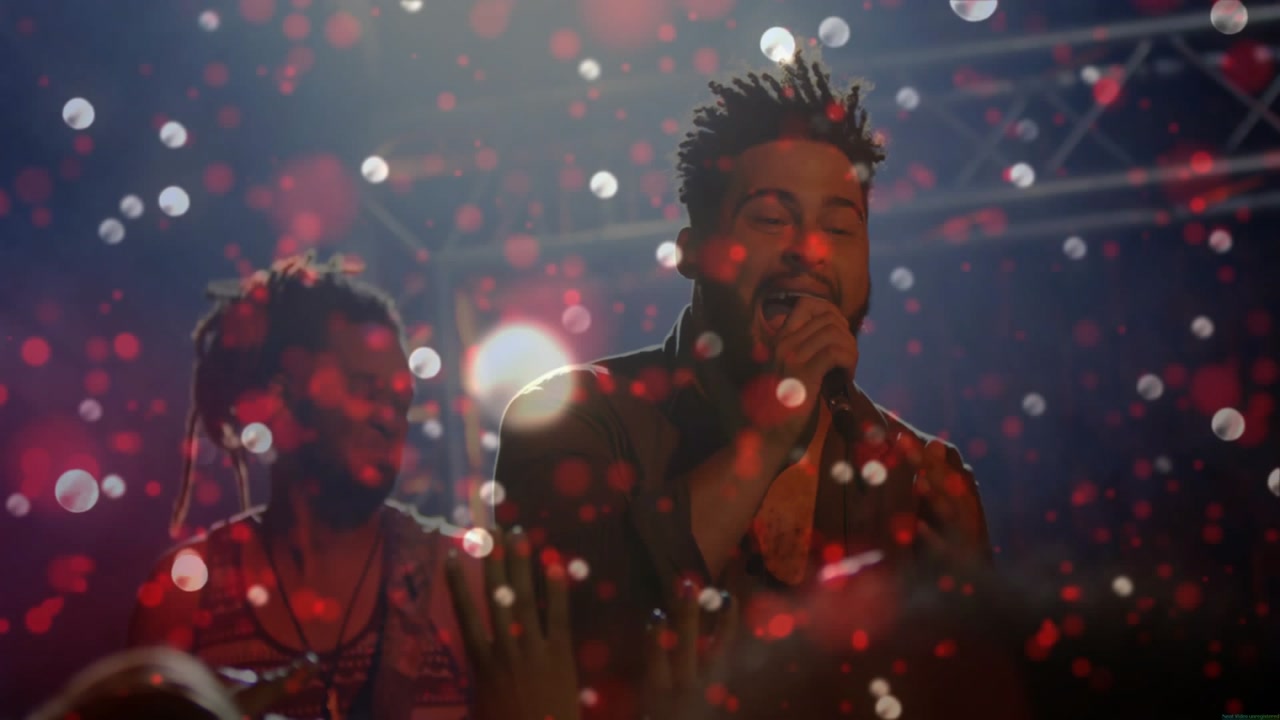 Lead singer starting song, singing into handheld mic, engaging crowd while red white bokeh drifting