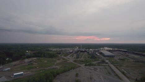 Aerial-drone-forward-moving-shot-over-an-old-mill-along-rural-countryside-on-a-cloudy-evening