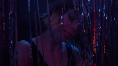 a young woman dances behind the glittering curtain