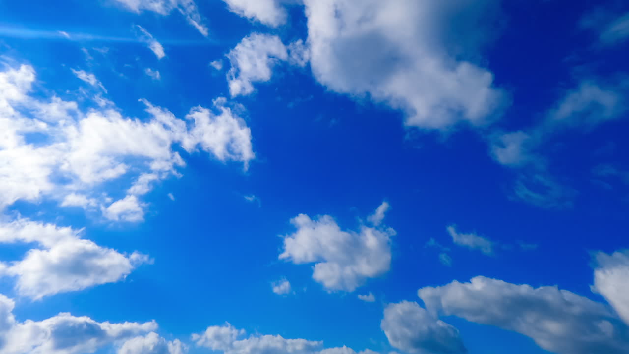 Amazing azure sky with small clouds quickly floating in the wind. Low angle perspective on summer sky. Timelapse.