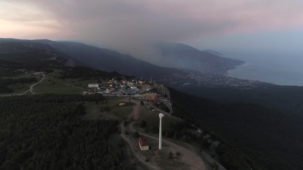 vista de la cima de la montaña con la ciudad costera al atardecer
