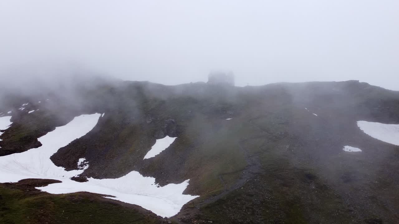 오스트리아 살츠부르크의 알프스 산맥에서 매우 구름이 많은 날씨에 산꼭대기에 서 있는 집