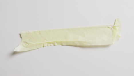 video de primer plano de un pedazo de papel amarillo roto sobre un fondo blanco