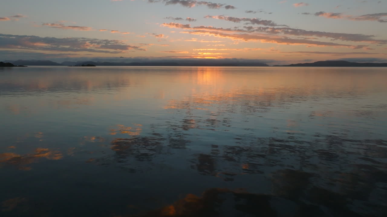 Aerial: Whitsundays Drone shot flying over a mirror reflective ocean during beautiful colourful sunrise. QLD, Australia