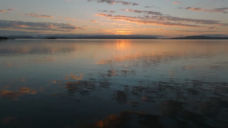aerial: whitsundays drone shot flying over a mirror reflective ocean during beautiful colourful sunrise. qld, australia