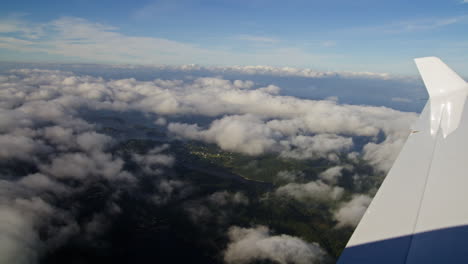 aerial shot from an aeroplane looking through clouds onto the mountains below