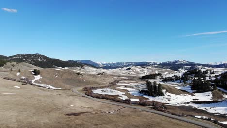 Drone-shot-of-snowy-hills-and-a-winding-road