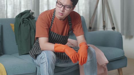소파 에 앉아 있고, 망진창 한 방 을 청소 하는 데 피곤 하기 때문 에 두통 을 고 있는 아시안 남성 집주인
