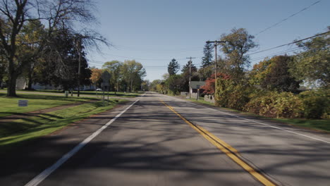 Drive-along-a-typical-street-of-an-American-town-on-a-clear-autumn-day.-Rear-window-view