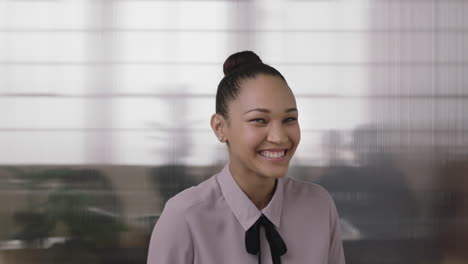 close up portrait of beautiful young mixed race business woman intern laughing cheerful enjoying fun in office workspace background