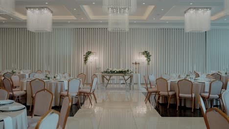 elegant wedding reception hall with white decor, chandeliers, and dining tables