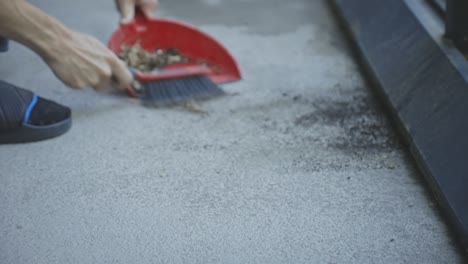 Hands-Using-A-Hand-Broom-And-Dustpan-In-Cleaning---close-up