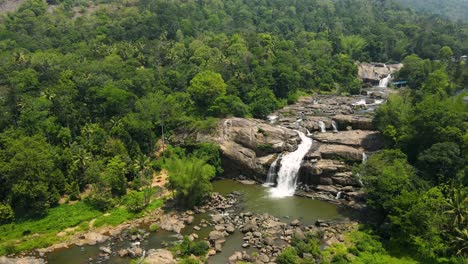 aerial drone shot of a tranquil waterfall flowing down the hills of munnar