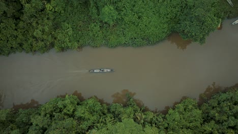 people in kayak cruising over amazon river along rainforest with trees and bush,4k - aerial top down