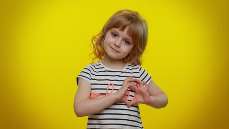 niña sonriente hace un gesto de corazón demuestra un signo de amor expresa buenos sentimientos y simpatía