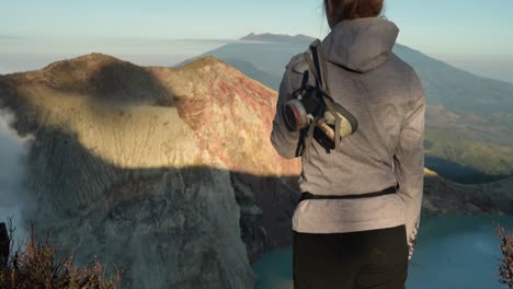 cute caucasian woman with gas mask enjoys view of indonesian volcano in java