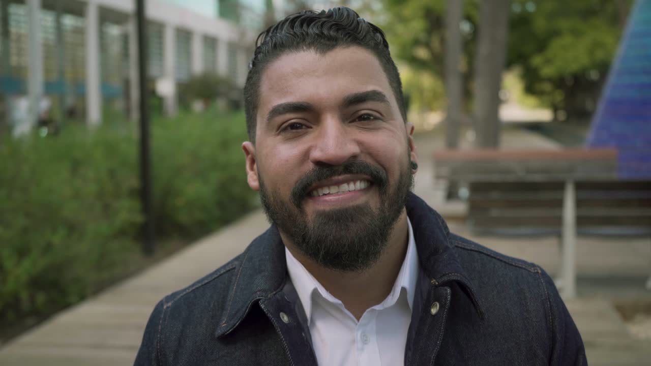 Homem barbudo bonito sorrindo para a câmera ao ar livre