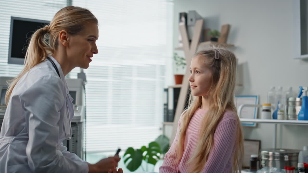 Doctor consulting young girl in modern medical office. Smiling pediatrician talk