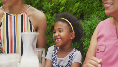 Glückliche-Afroamerikanische-Großmutter-Mit-Enkelin-Beim-Frühstück-Mit-Der-Familie-Im-Garten