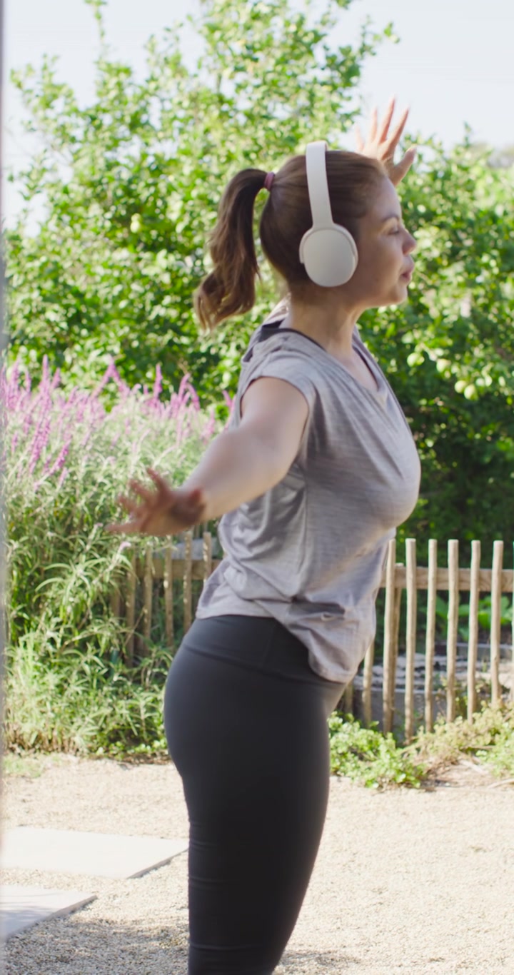 Voksen kvinde laver fitness opvarmning med smartwatch, strækker armene fra samlede hænder for mobilitet.
