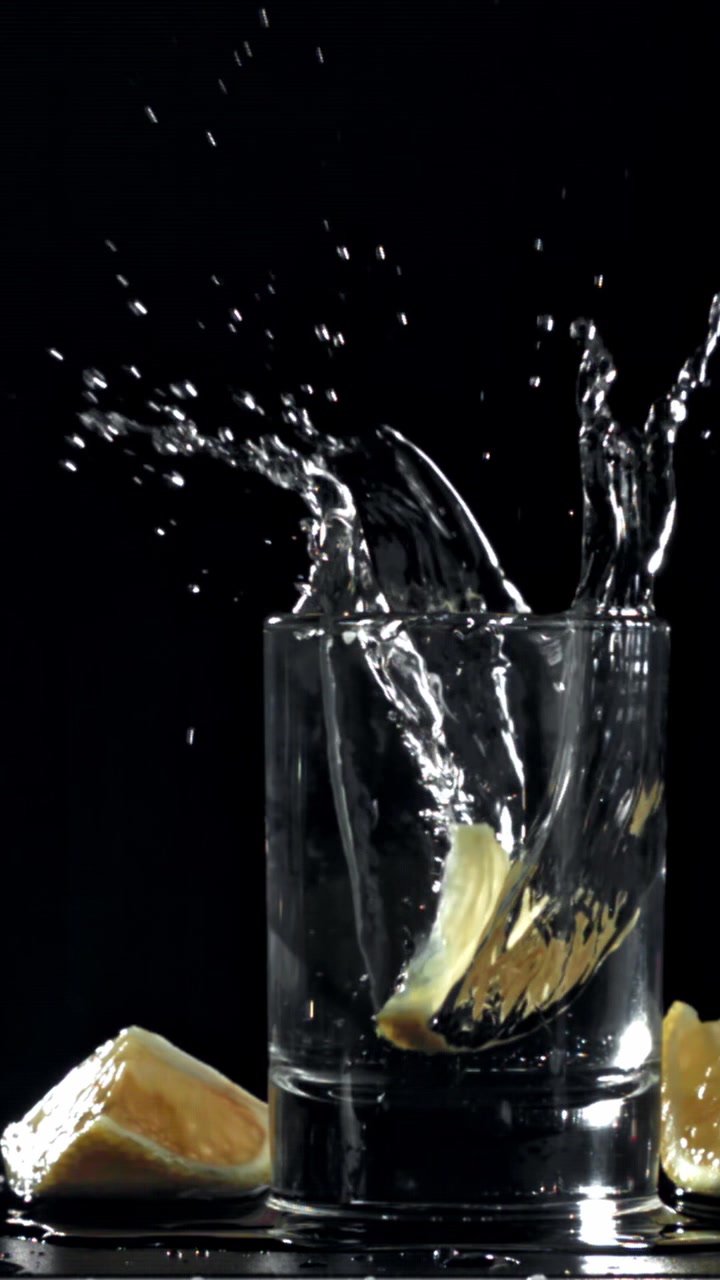 Fetta di limone che si tuffa in un bicchiere d'acqua al rallentatore