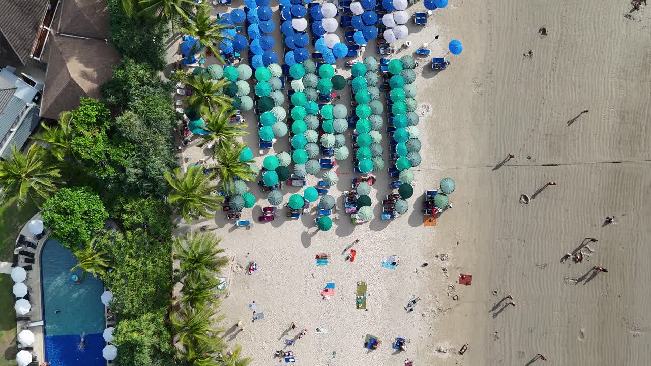 드론 영상은 태국 푸켓의 이 많은 날에 활기찬 우산과 해변을 찾는 사람들을 포착하여 활기찬 해안 풍경을 보여줍니다.