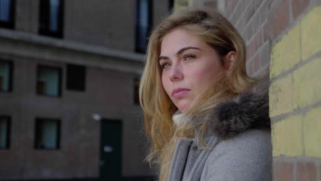 serious young woman poses against a brick wall