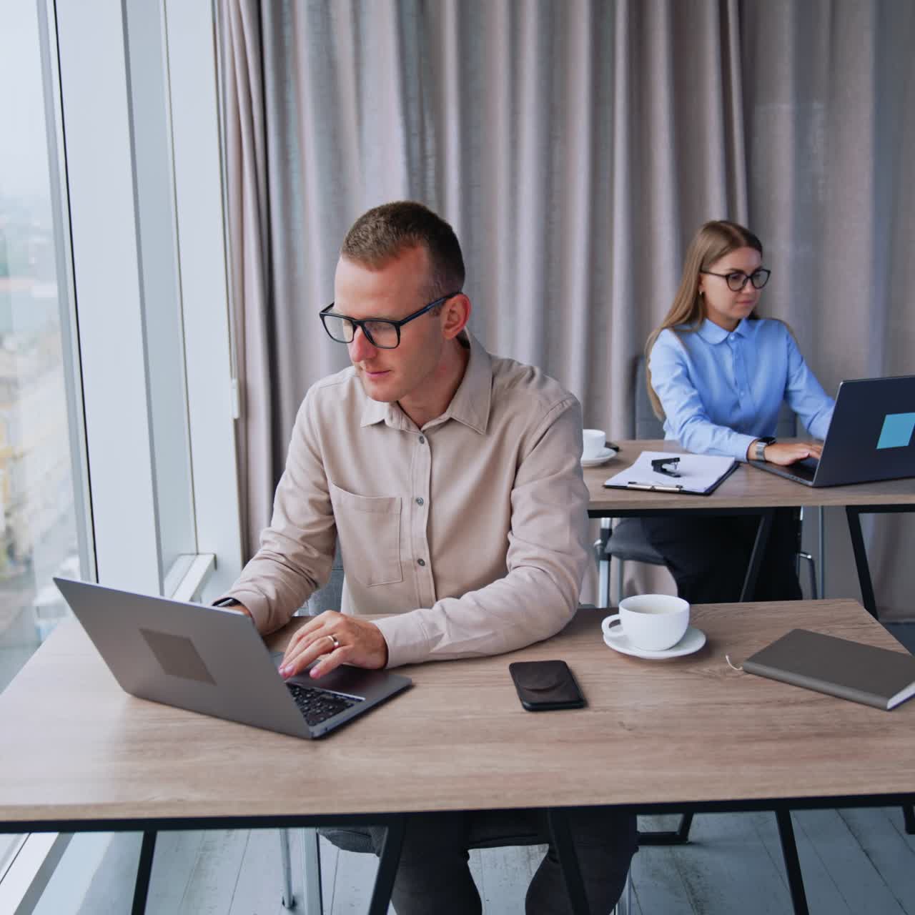 Persone che lavorano al computer sedute alla scrivania in ufficio. Lavoro in un ufficio moderno in una stanza luminosa con una grande finestra panoramica.