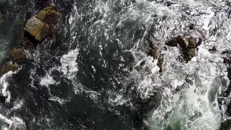 Rising-top-down-aerial-view-of-crashing-waves-on-large-rocks