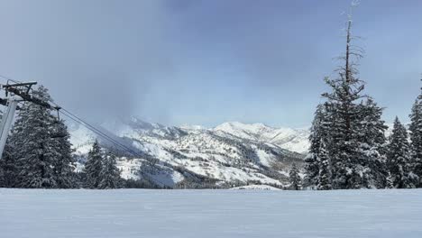 landscape shot on the summit of a ski resort in the rocky mountains in utah with the lift passing by and surrounded by snow covered pine trees on a warm winter day