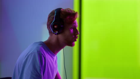 excited player losing game in neon room closeup. upset man taking headphones off