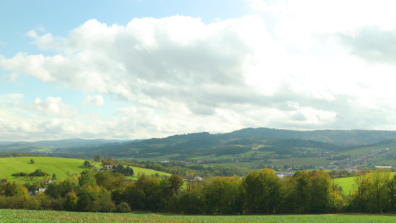 마을 위로 움직이는 구름과 그 그림자는 4k 60fps로 캡처된 화창한 날 높은 언덕의 배경인 베스키드 국립공원 지역의 풍경과 들판 위의 땅에 반사됩니다.