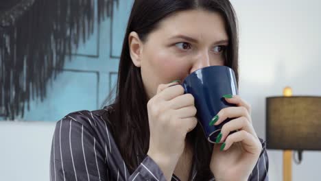 close up of young woman sitting on the bed and enjoying morning coffee