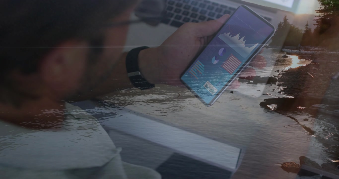 Man tilting smartphone at desk, moving river overlay rightward and highlighting finance charts